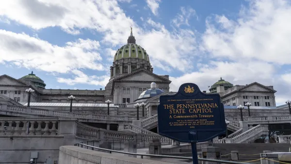 View of Pennsylvania state capitol building with historical plaque in foreground.